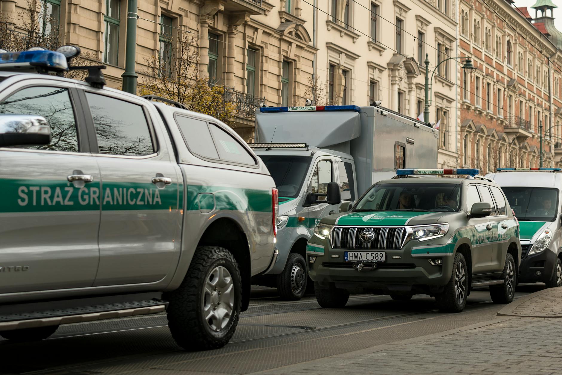 Straż Graniczna vehicles parked along a historic street in Kraków, Poland.
