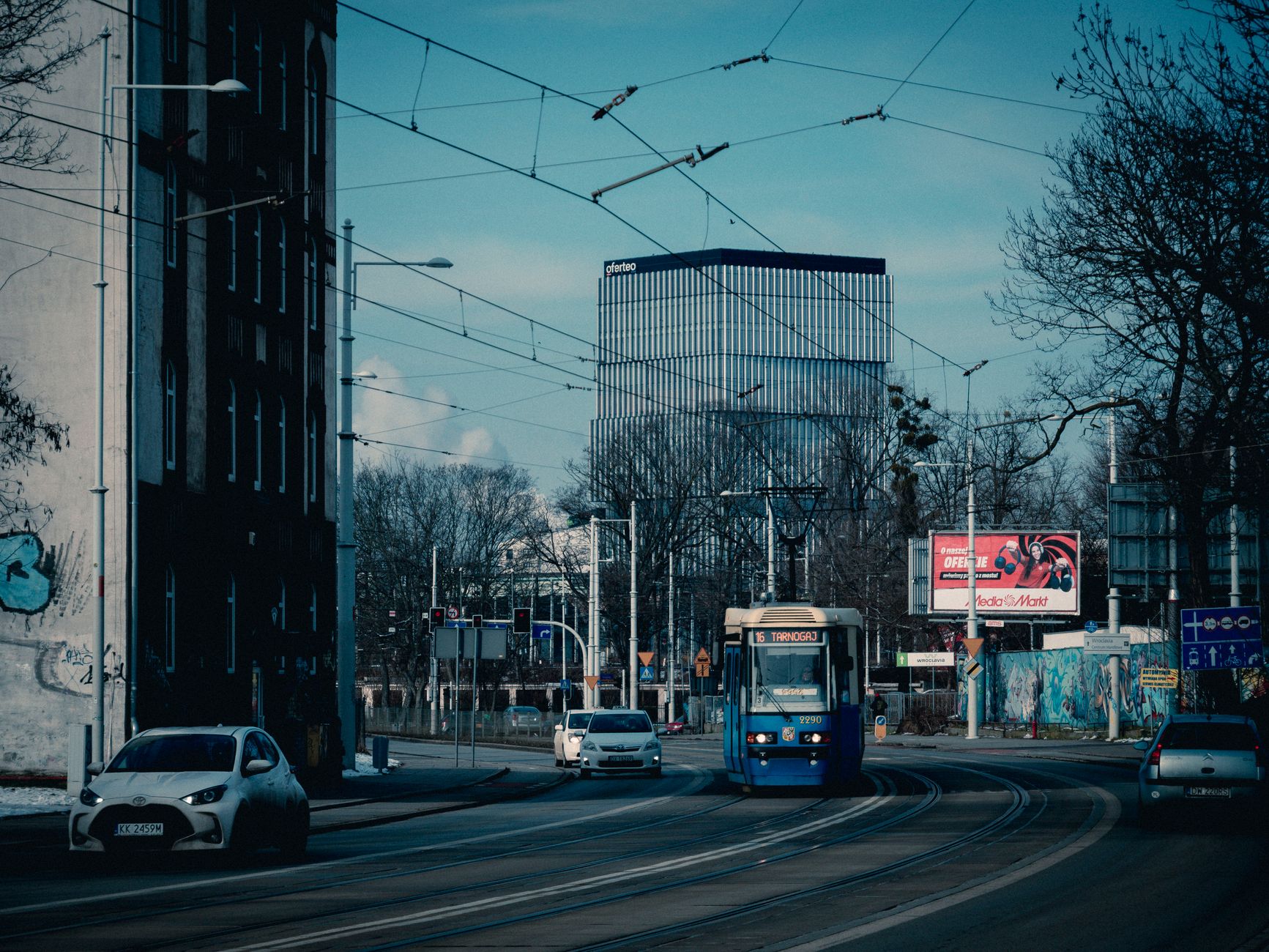 City street with tram, cars, and modern office building.