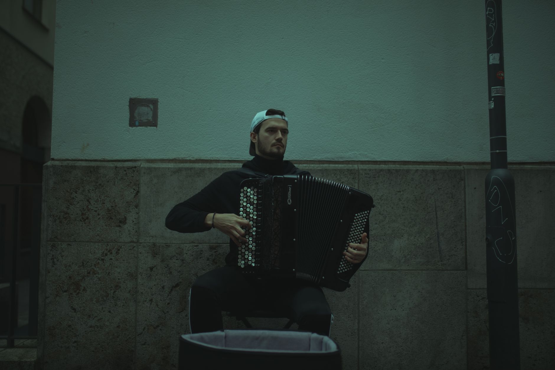 A street musician playing an accordion in an urban environment, creating a moody atmosphere.