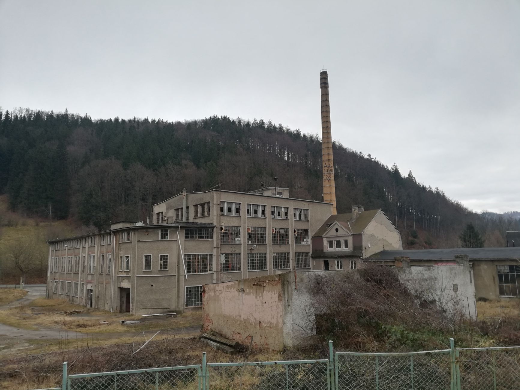 Weathered industrial building nestled in the forested mountains of Poland.