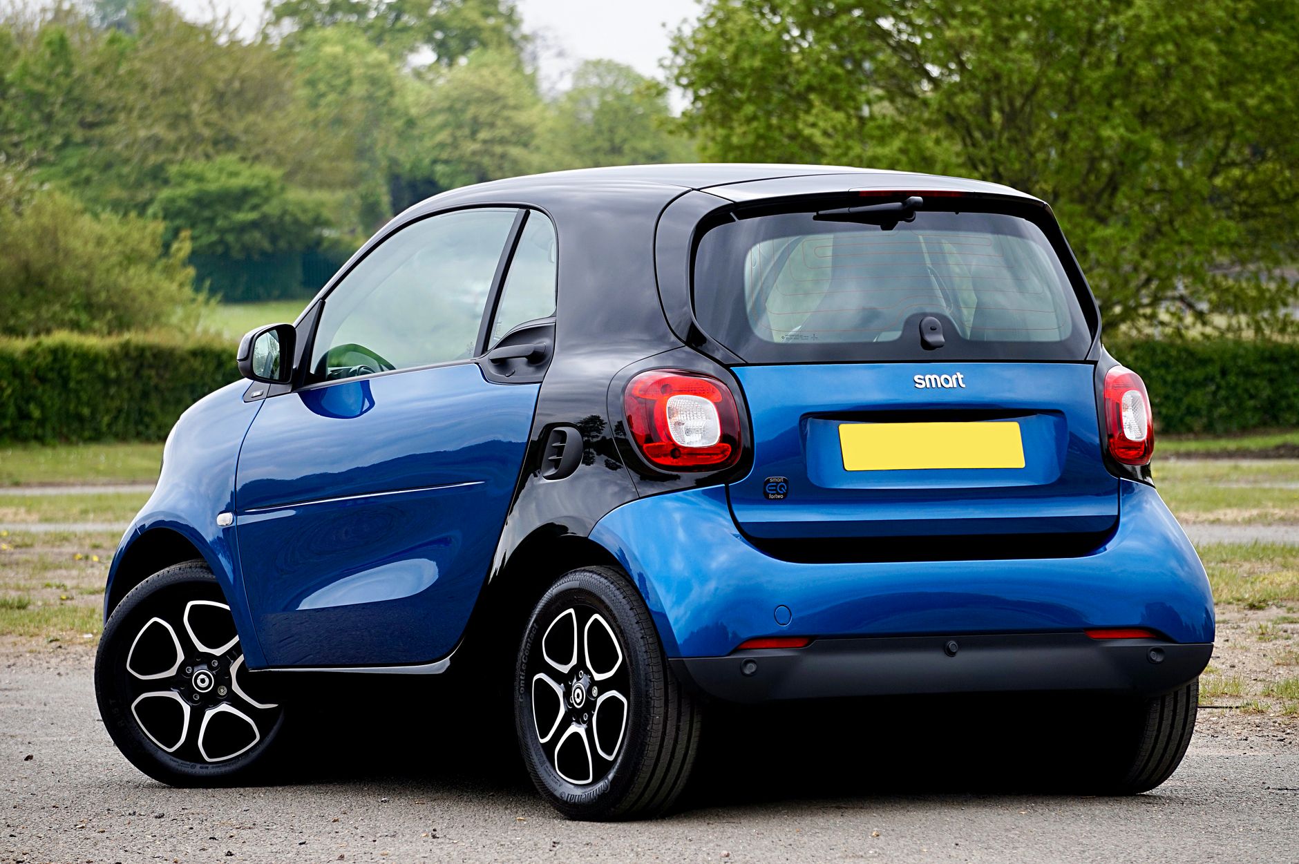 A sleek blue electric smart car parked outdoors, showcasing modern automotive design.