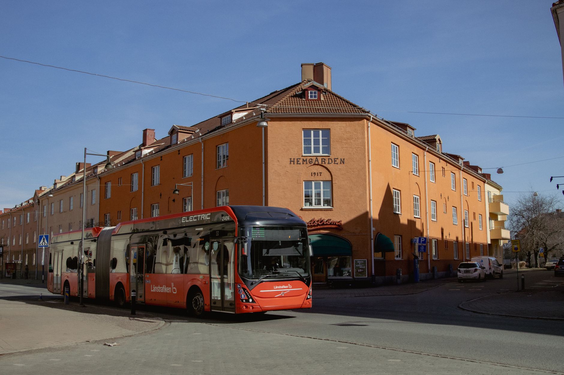 Electric city bus passing historic building in Jönköping, Sweden on a sunny day.