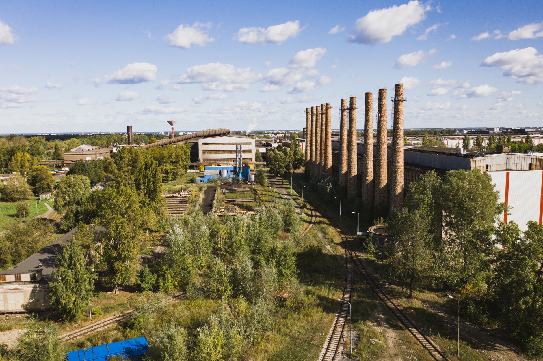 Aerial shot of an industrial facility featuring tall brick chimneys on a sunny day.