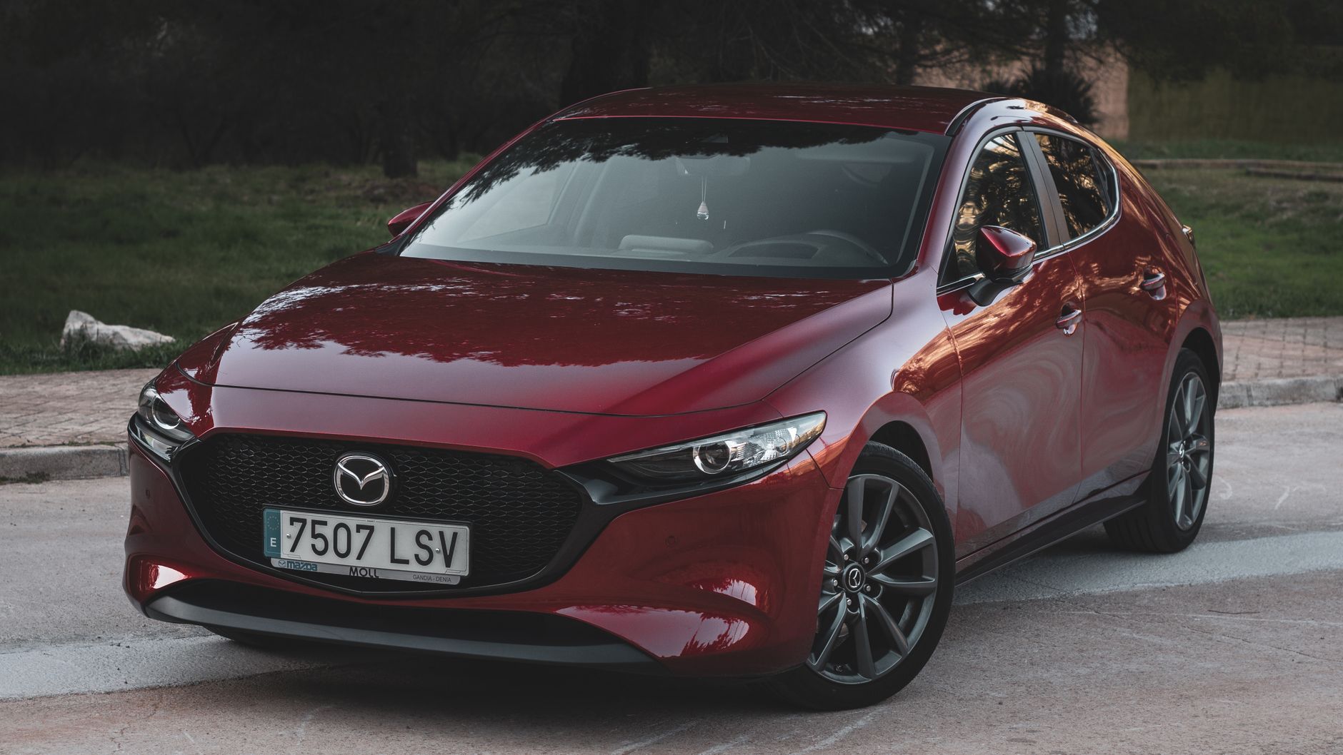 Stylish red Mazda 3 parked outdoors, showcasing a sleek, modern design.