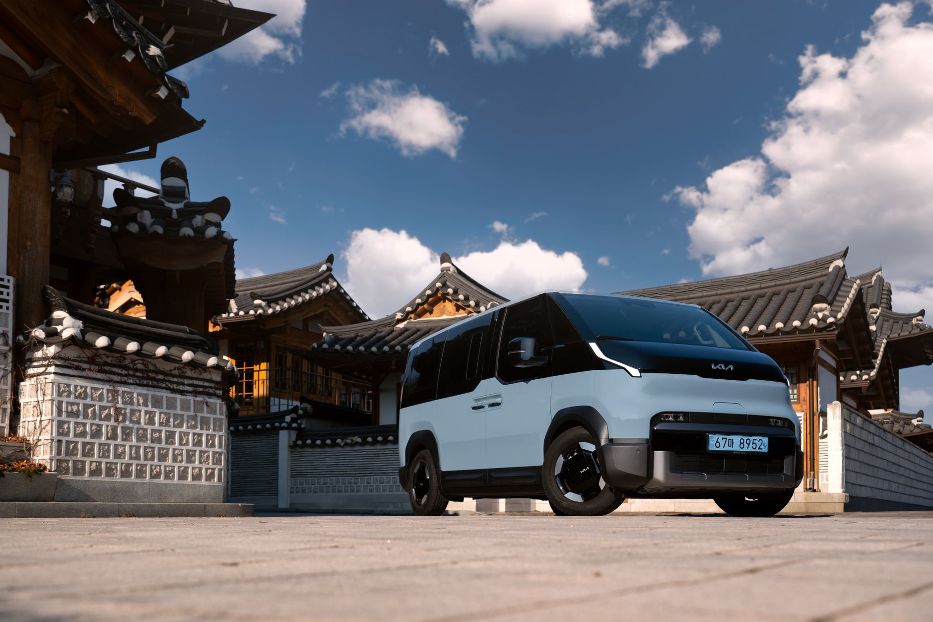 Electric van parked in a traditional village with historic architecture and clear blue skies.
