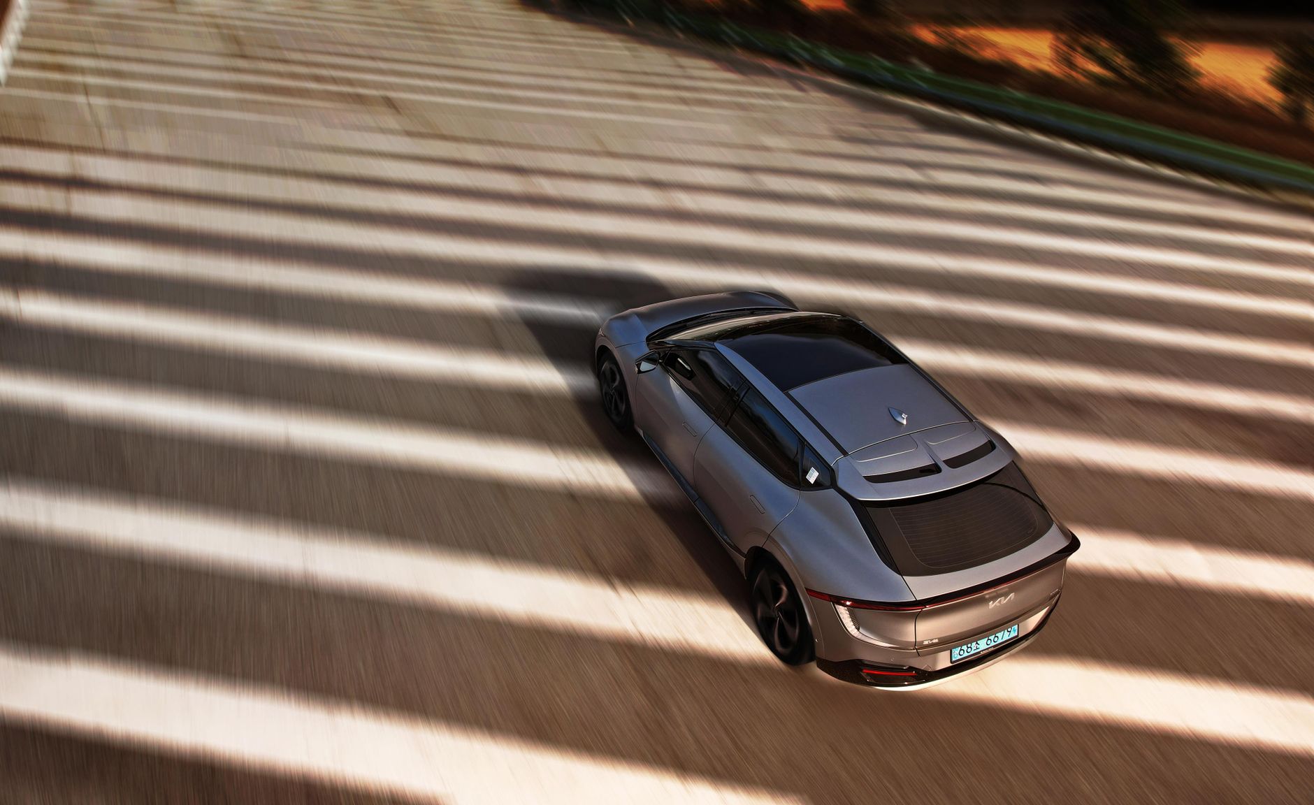 Aerial shot of an electric car driving on a sunny road.