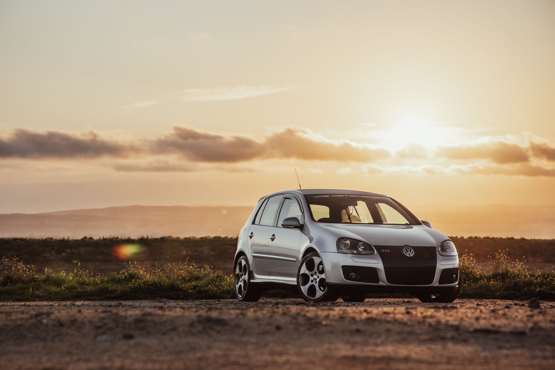 A Volkswagen hatchback car parked outdoors during sunset with clear copy space.